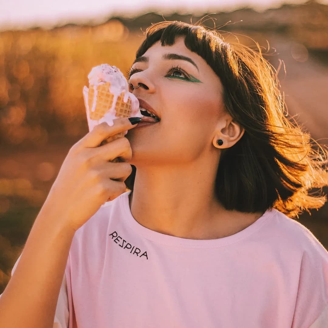 Modelo tomando sorvete com a camiseta Respira rosa, a palavra bordada no peito